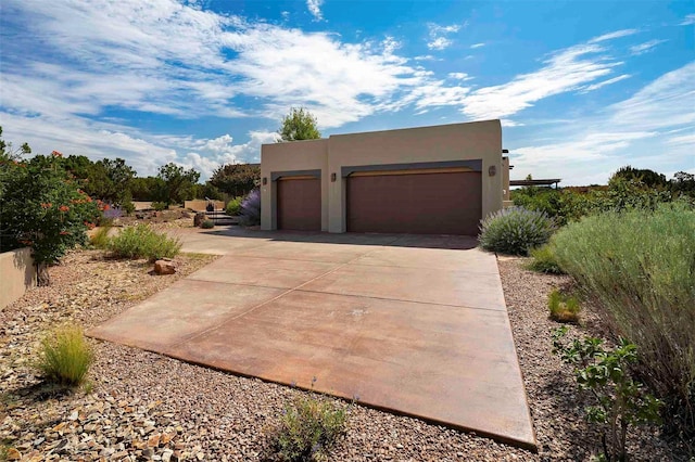 view of front of house with a garage, concrete driveway, and stucco siding