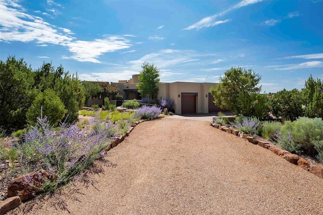 southwest-style home featuring a garage, dirt driveway, and stucco siding