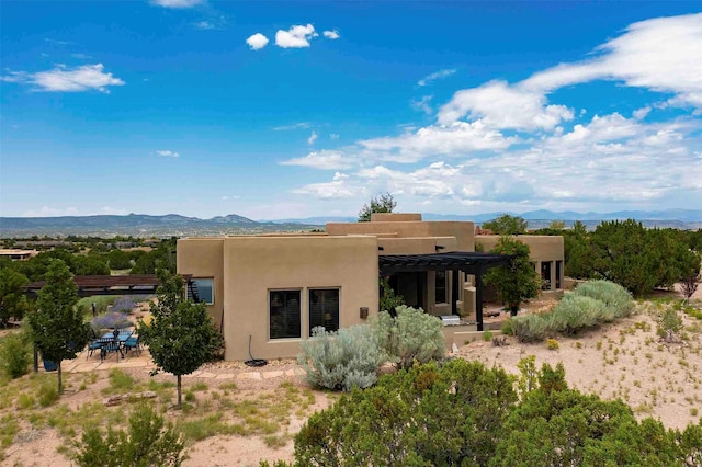 rear view of house featuring a pergola, a mountain view, a patio, and stucco siding