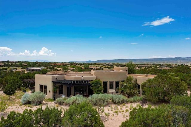 back of property featuring a mountain view, a pergola, and stucco siding