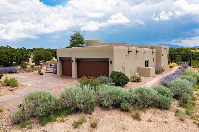 southwest-style home featuring concrete driveway, an attached garage, and stucco siding