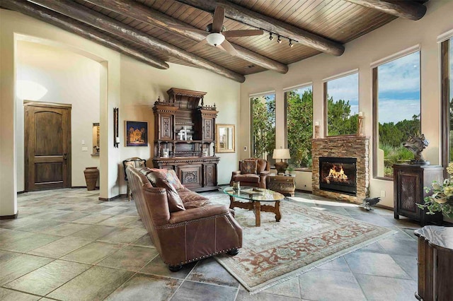 interior space with wooden ceiling, a ceiling fan, baseboards, beam ceiling, and a glass covered fireplace