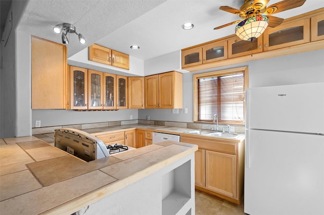 kitchen with light brown cabinetry, sink, white appliances, ceiling fan, and a textured ceiling