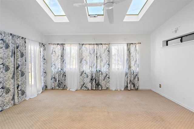 carpeted spare room featuring lofted ceiling with skylight