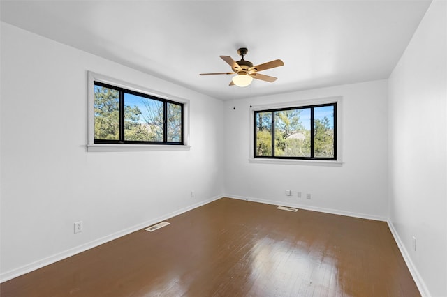 spare room with ceiling fan, a healthy amount of sunlight, and dark hardwood / wood-style floors