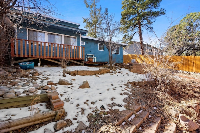 snow covered back of property featuring a deck