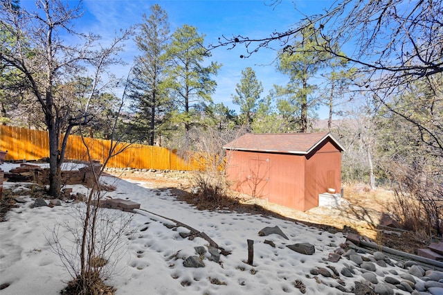 yard layered in snow featuring a storage shed