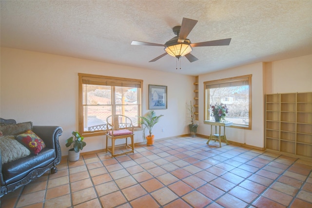 living area with ceiling fan, a wealth of natural light, a textured ceiling, and light tile patterned floors