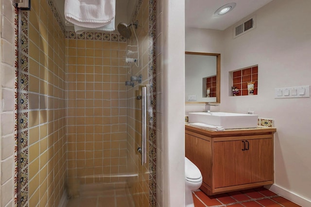 bathroom with vanity, toilet, tile patterned flooring, and a tile shower