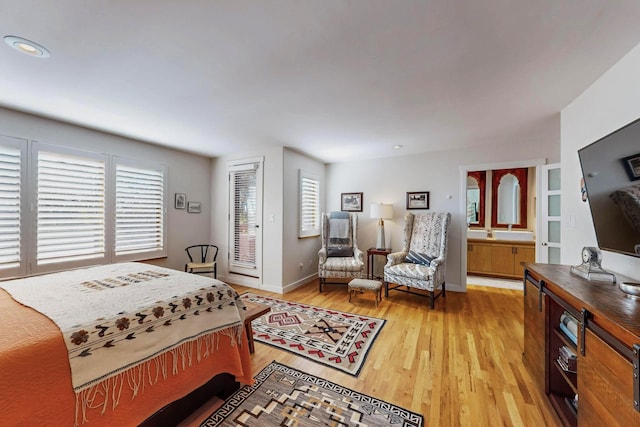 bedroom with ensuite bathroom and light hardwood / wood-style floors