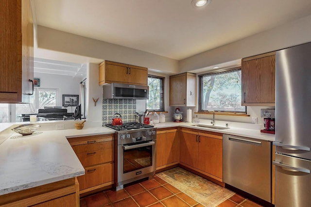 kitchen with appliances with stainless steel finishes, sink, a wealth of natural light, and decorative backsplash