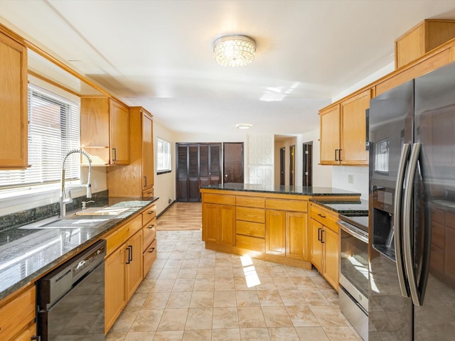 kitchen with a peninsula, dark stone counters, stainless steel appliances, and a sink