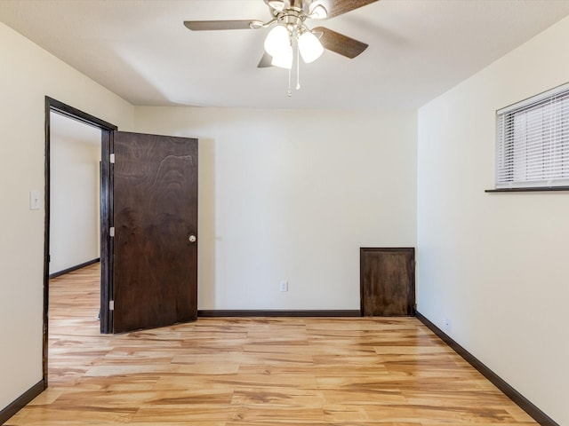 spare room with a ceiling fan, light wood-style flooring, and baseboards