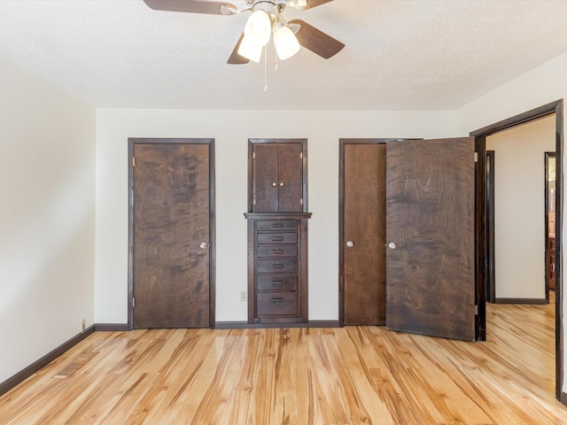 unfurnished bedroom with a textured ceiling, wood finished floors, a ceiling fan, and baseboards