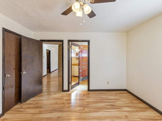 empty room with light wood finished floors, ceiling fan, baseboards, and a textured ceiling