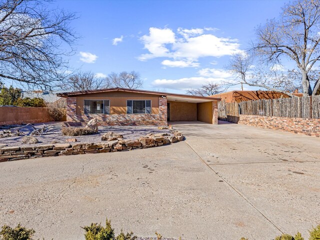 view of front facade with an attached carport, concrete driveway, and fence