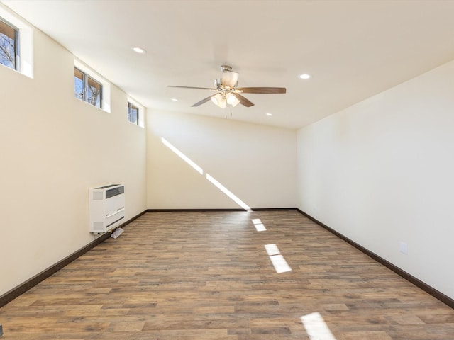 unfurnished room with recessed lighting, wood finished floors, a ceiling fan, baseboards, and heating unit