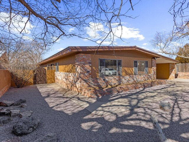 view of front of house with fence, an attached carport, concrete driveway, and stucco siding