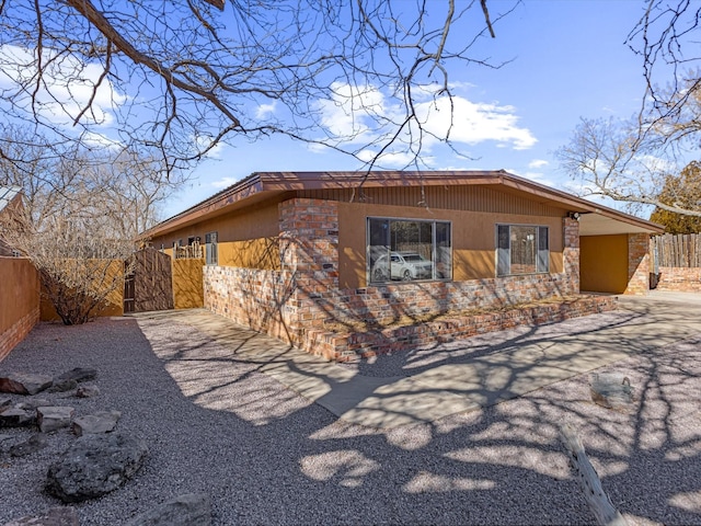 view of side of home with a gate, fence, and driveway