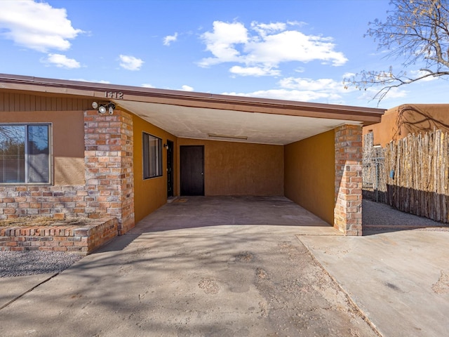 view of parking / parking lot with driveway, fence, and a carport