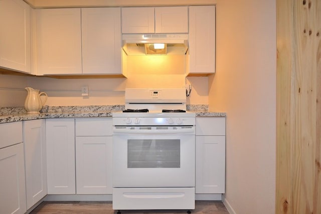 kitchen with white cabinetry, white gas stove, light stone counters, and light hardwood / wood-style floors