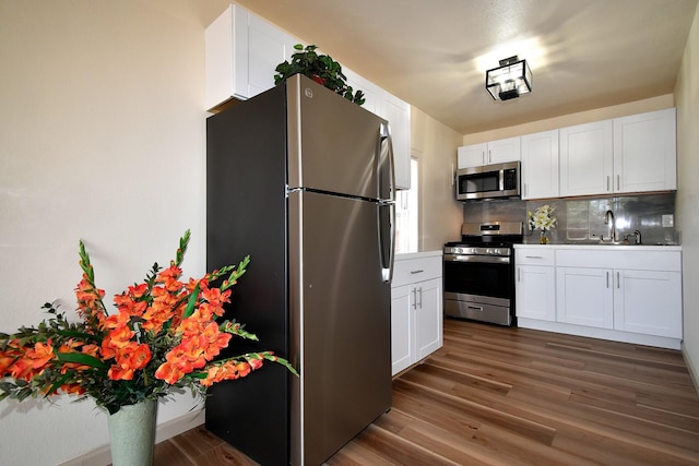 kitchen with stainless steel appliances, dark hardwood / wood-style floors, sink, and white cabinets