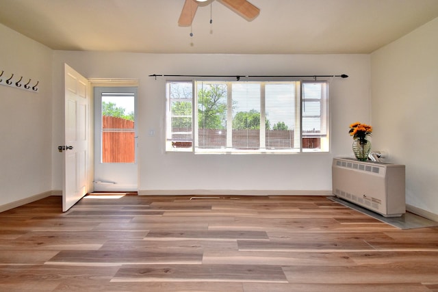 empty room with heating unit, hardwood / wood-style flooring, and ceiling fan