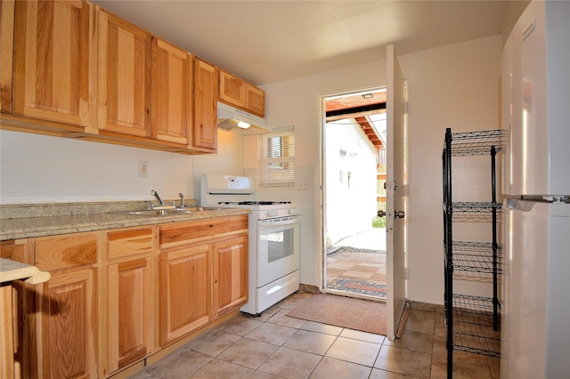 kitchen with light stone countertops, white range with gas cooktop, sink, and light tile patterned floors