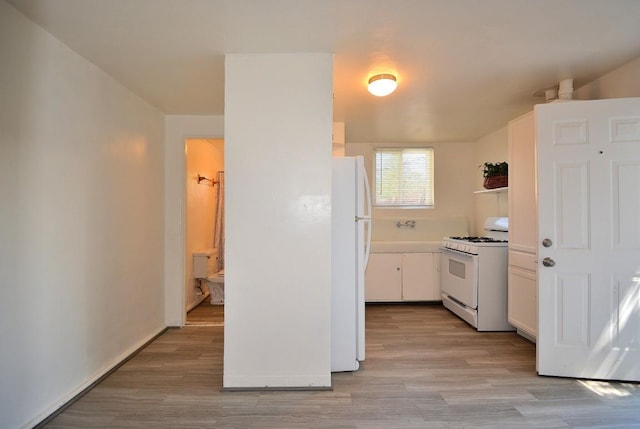 kitchen with white appliances, white cabinets, and light wood-type flooring