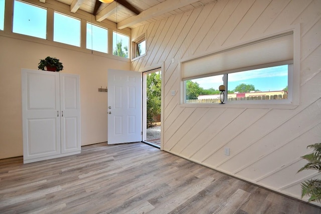 entryway featuring beam ceiling, wooden walls, wood ceiling, and light hardwood / wood-style floors