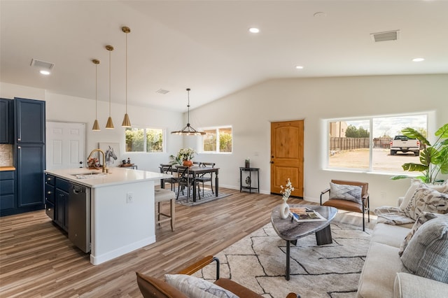 living room with vaulted ceiling, sink, and light hardwood / wood-style flooring