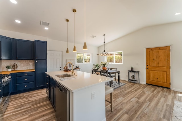 kitchen with sink, appliances with stainless steel finishes, hanging light fixtures, a center island with sink, and blue cabinets