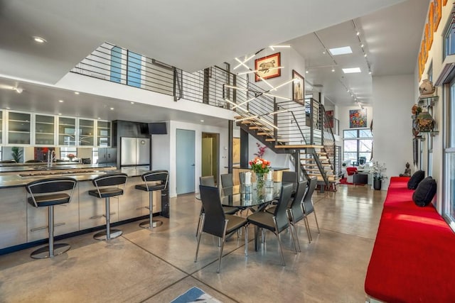 dining area with a towering ceiling, concrete flooring, and rail lighting