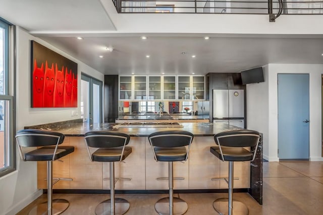 kitchen with tasteful backsplash, a kitchen bar, stainless steel fridge, and kitchen peninsula