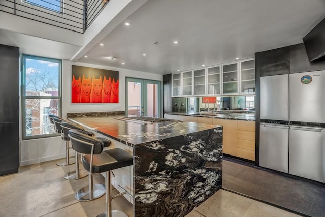 kitchen with a kitchen bar, french doors, kitchen peninsula, stainless steel gas stovetop, and light brown cabinets