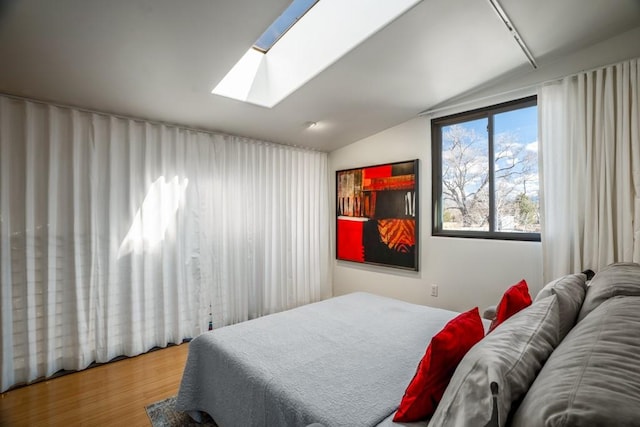 bedroom with hardwood / wood-style flooring and vaulted ceiling with skylight