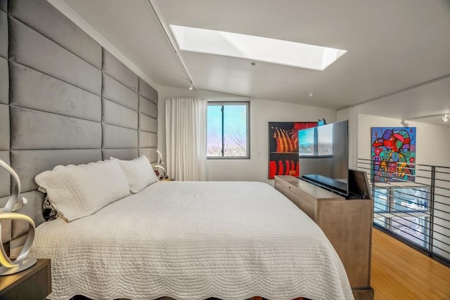 bedroom with lofted ceiling with skylight and hardwood / wood-style floors