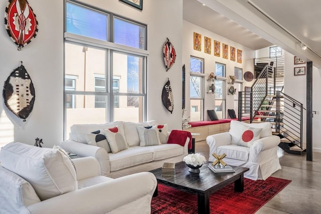 living room featuring concrete flooring, rail lighting, and a high ceiling