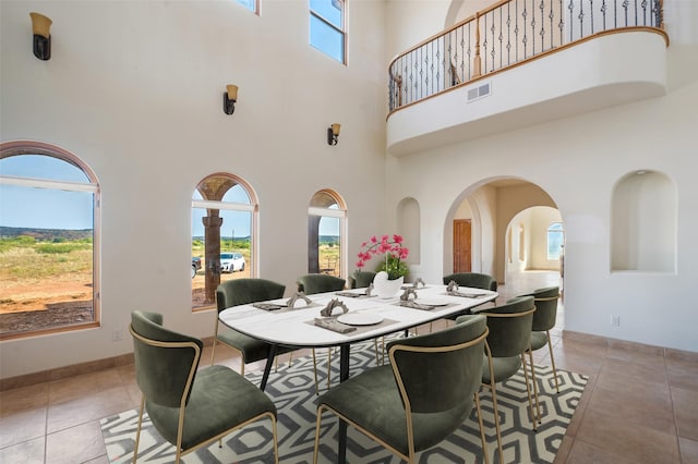 tiled dining room featuring a healthy amount of sunlight and a high ceiling