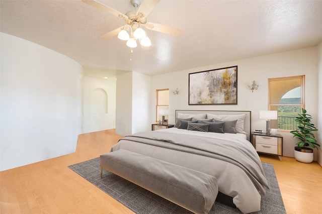 bedroom featuring ceiling fan, a textured ceiling, and light wood-type flooring