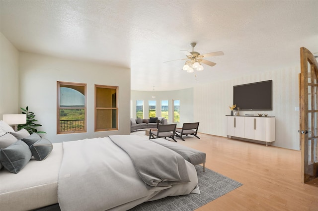 bedroom featuring ceiling fan, light hardwood / wood-style flooring, and a textured ceiling