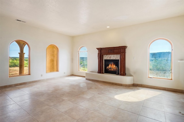 unfurnished living room featuring light tile patterned floors and a high end fireplace