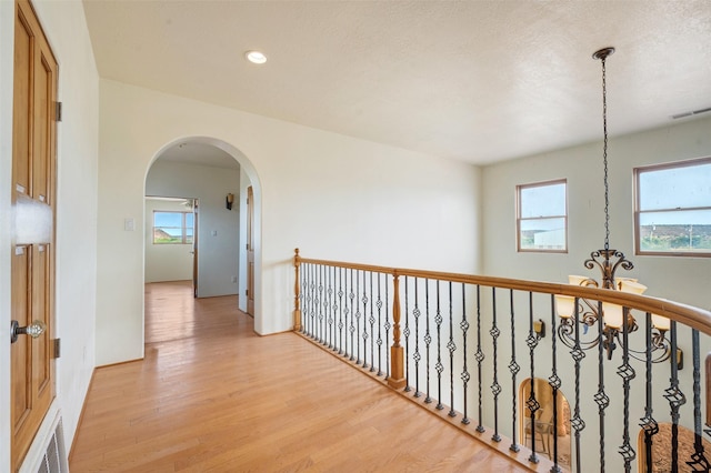 hallway with an inviting chandelier and light hardwood / wood-style flooring