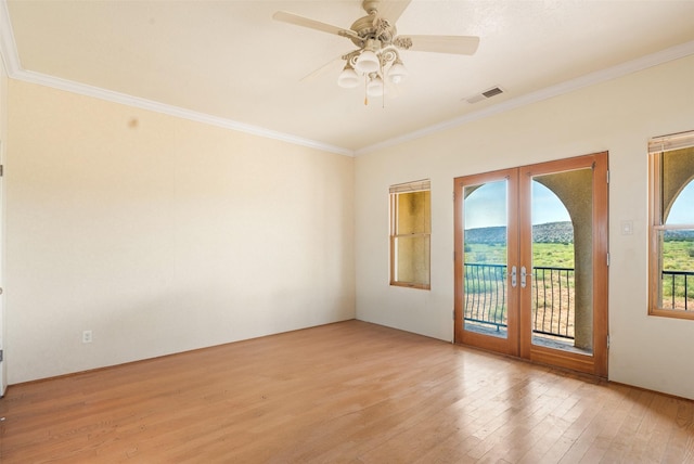 empty room with french doors, ceiling fan, ornamental molding, and light wood-type flooring