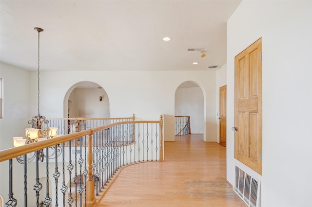 corridor featuring an inviting chandelier and light hardwood / wood-style flooring