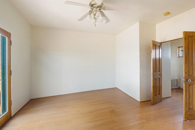 unfurnished room with ceiling fan, radiator heating unit, and light hardwood / wood-style flooring