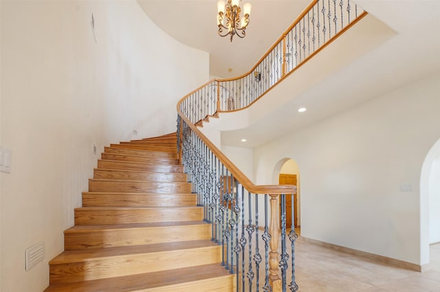 stairs featuring a high ceiling, tile patterned flooring, and a notable chandelier