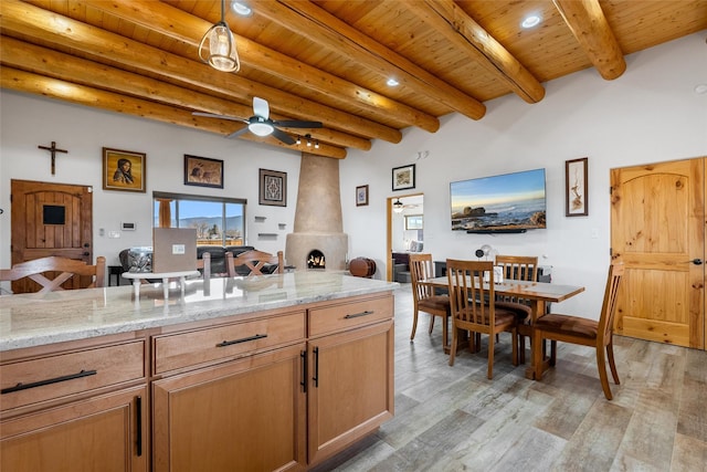 kitchen featuring ceiling fan, light stone counters, light hardwood / wood-style floors, wooden ceiling, and beamed ceiling