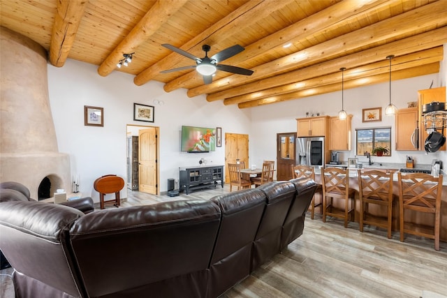 living room with beamed ceiling, sink, ceiling fan, light hardwood / wood-style floors, and wooden ceiling