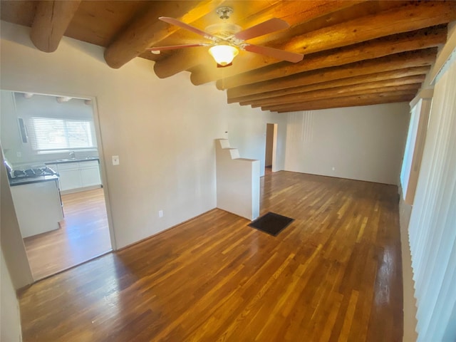 empty room featuring wood-type flooring, sink, ceiling fan, and beam ceiling